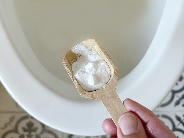 Sprinkling baking soda into toilet