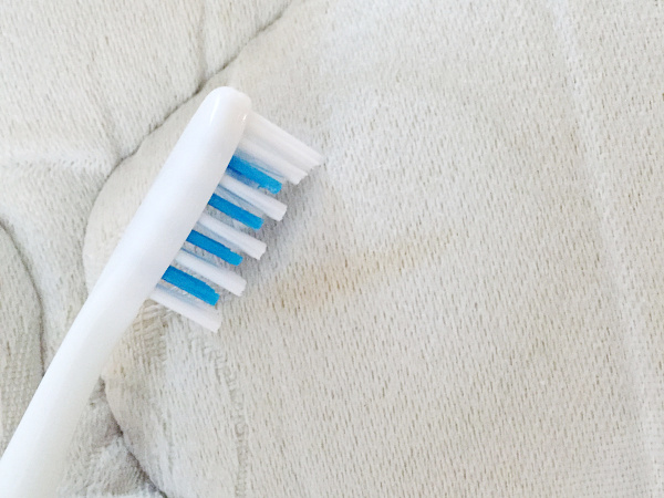 Using toothbrush to clean stains on mattress