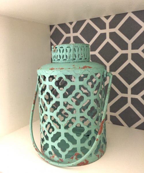 Shelving unit with fabric back to create pattern. Displayed with small vintage lantern