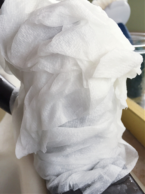 Vinegar soaked paper towels wrapped around faucet to remove hard water stains