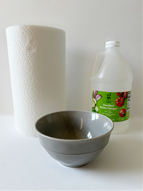 Everything needed to remove hard water stains: vinegar, paper towels and a bowl