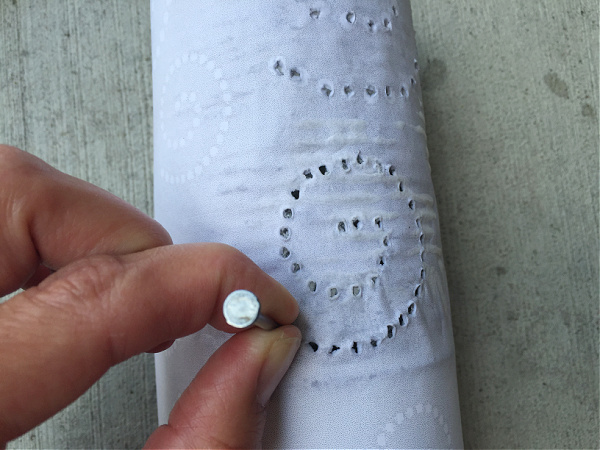 Punching holes in a pattern into a tin can to make a lantern