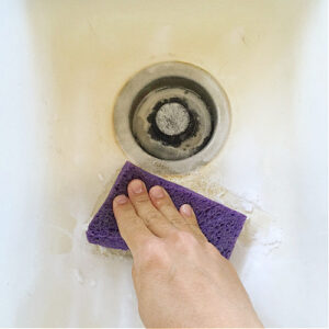 Scrubbing a porcelain sink with baking soda