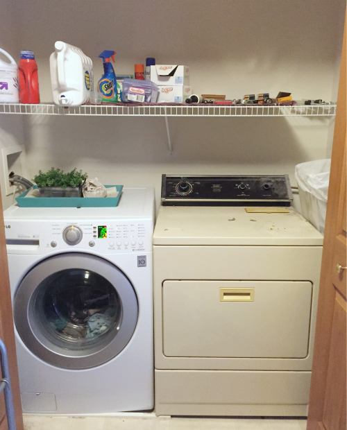 Laundry room prior to makeover. Mismatched appliances and wire shelving above washer and dryer