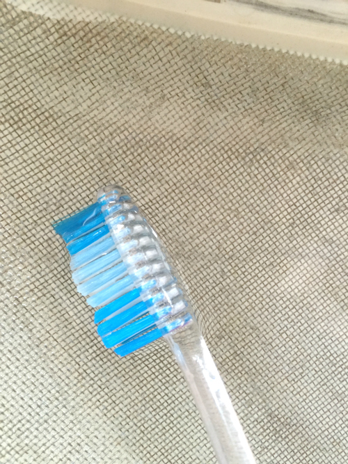 Cleaning a dryer lint trap with a toothbrush