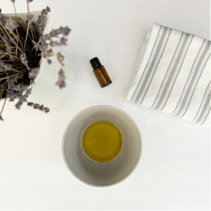 Homemade Furniture Polish in bowl with towel and bottle of essential oil