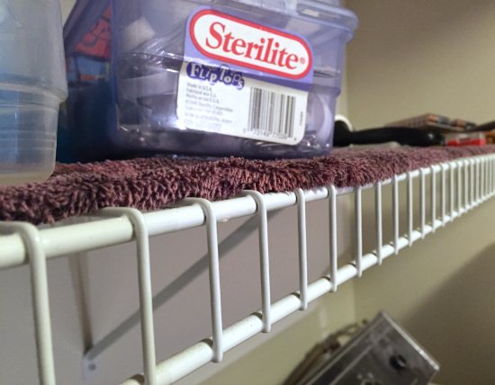 Before image of wire shelving in a laundry room covered with a towel to prevent items from falling through the cracks