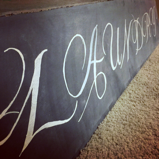 Cardboard made into chalkboard sign with the word Laundry in chalk lettering