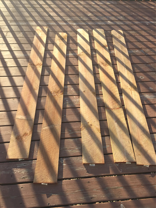 Cedar picket fence posts drying on deck before being used to make a faux wood shelf