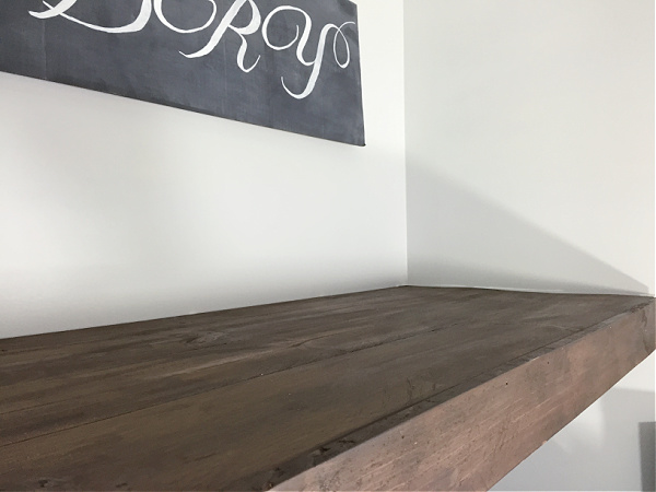 Close up of faux wood shelf that is covering wire shelf in a laundry room