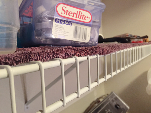 Ugly wire shelf in laundry room covered with a towel to prevent things from falling through