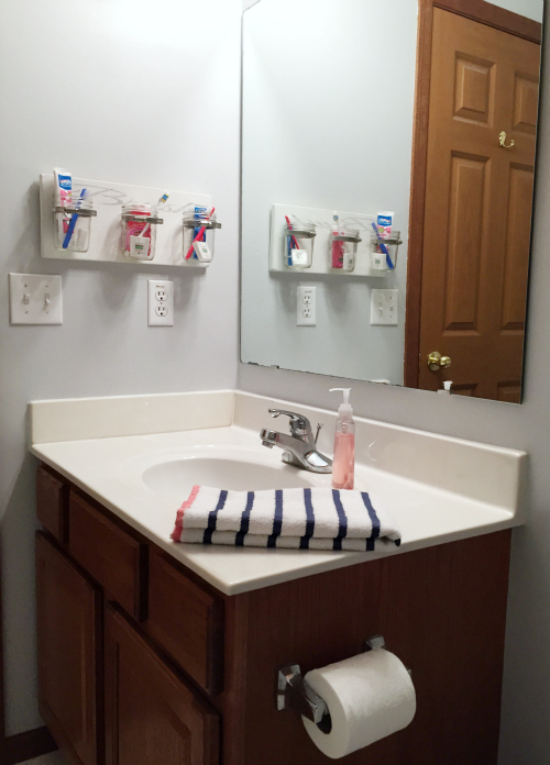 DIY Mason Jar Toothbrush holder displayed on the wall in a kids bathroom