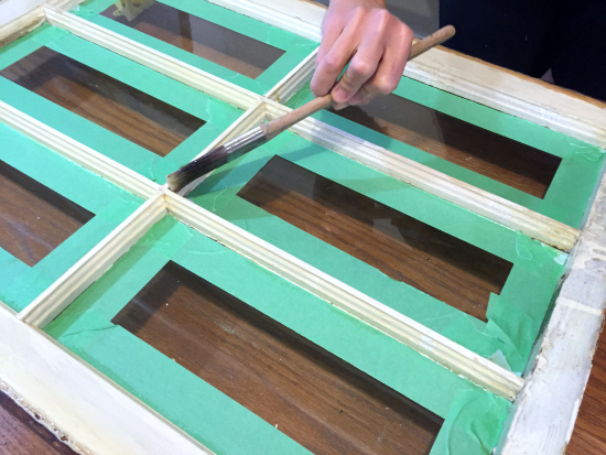 Applying polyurethane to an old wood window to seal the paint