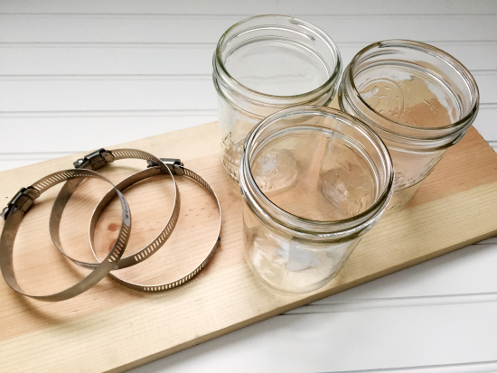 Items needed to make a DIY Mason Jar Toothbrush Holder: Wood, mason jars, and hose clamps