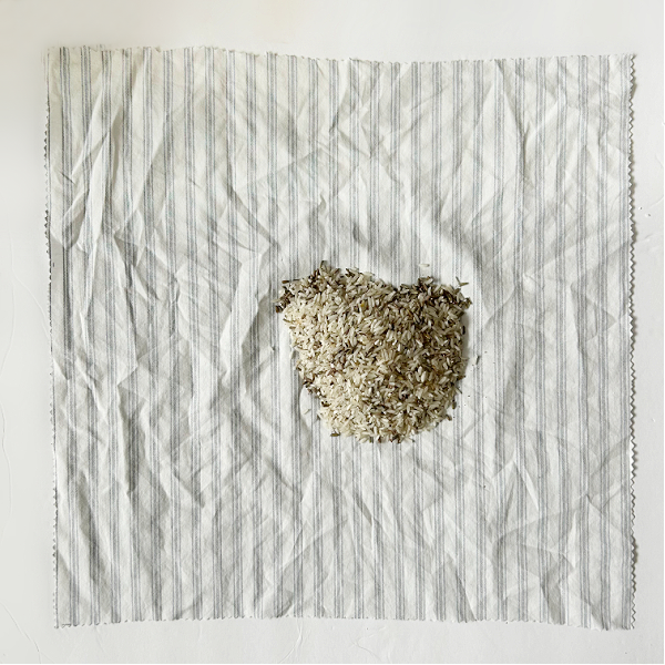 Scoop of DIY scented sachet mix in middle of a square piece of fabric