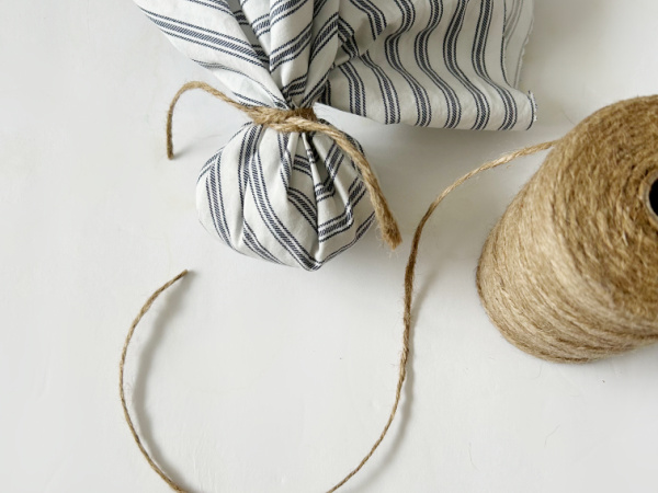 Tying twine around fabric to make a DIY drawer sachet