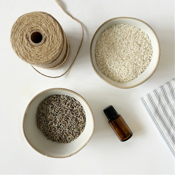 Ingredients needed to make DIY lavender sachets for drawers and closets: rice, essential oil, dried lavender, fabric and twine