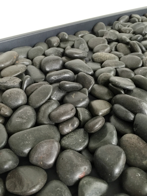 Black river rocks sitting in a plastic boot tray