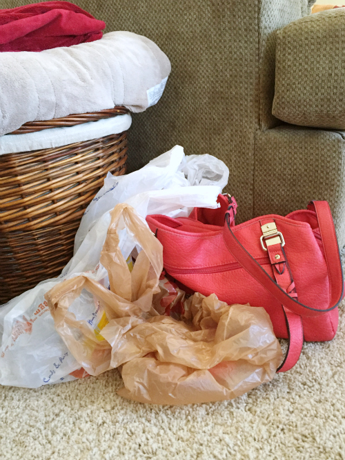Plastic bags and purse sitting next to couch