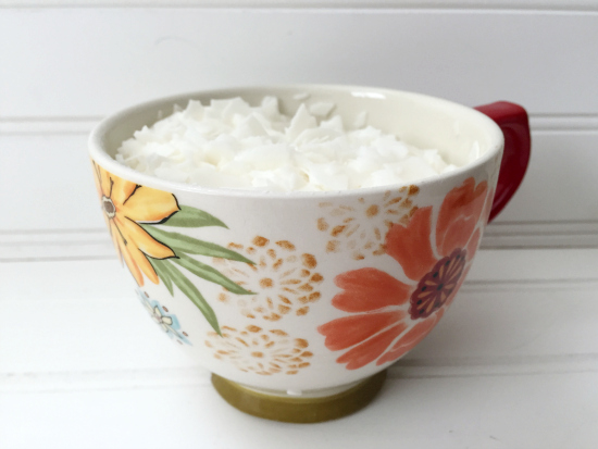 Floral mug holding soy wax flakes in order to make a DIY candle