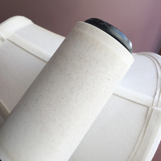 Rolling lint roller onto a lamp shade to remove dust.