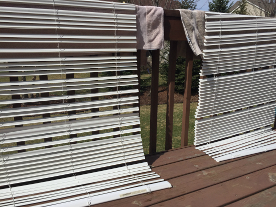 Cleaning Plastic Mini Blinds and allowing them to air dry on towels draped over a deck railing