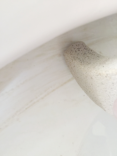 Scrubbing brown toilet stains with pumice stone