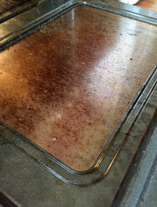 Brown stains on glass oven door before cleaning