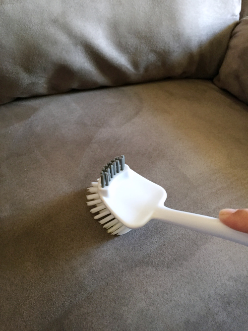 Using a soft bristle brush to loosen fibers after cleaning a microfiber couch