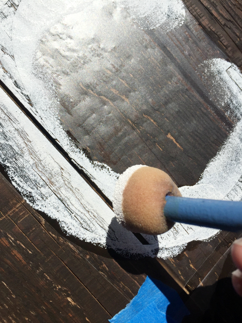 Using sponge brush to apply white paint to DIY Barnwood Sign