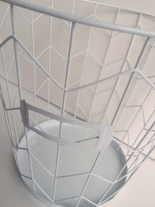 White wire wastebasket that will be used to hold toilet paper