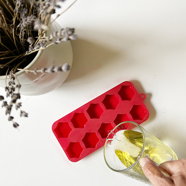 Pouring scented wax into a silicone mold to make homemade wax melts