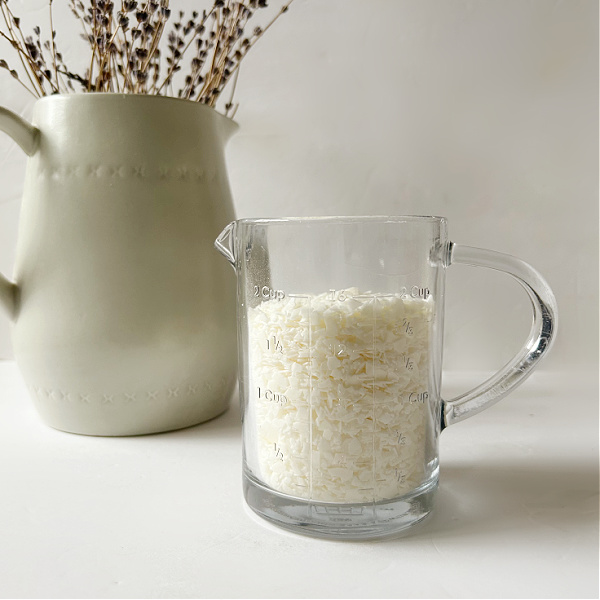 Liquid measuring cup filled with soy wax flakes