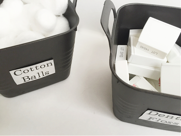 Spray painted dollar store bins holding cotton balls and dental floss