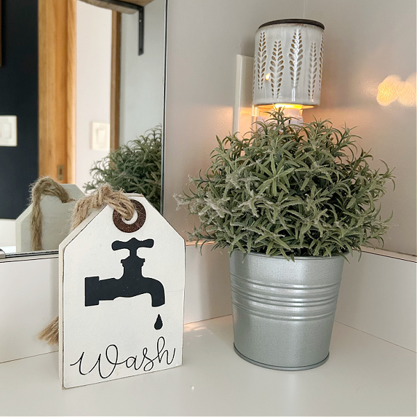 Plug-in Wax Warmer in Bathroom above counter with faux plant and small wooden "wash" sign