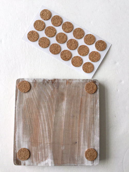 Applying cork pads to the bottom of DIY white washed wooden coasters