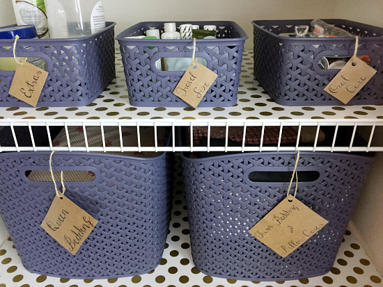 Plastic storage bins labeled and used for bedding and toiletries.