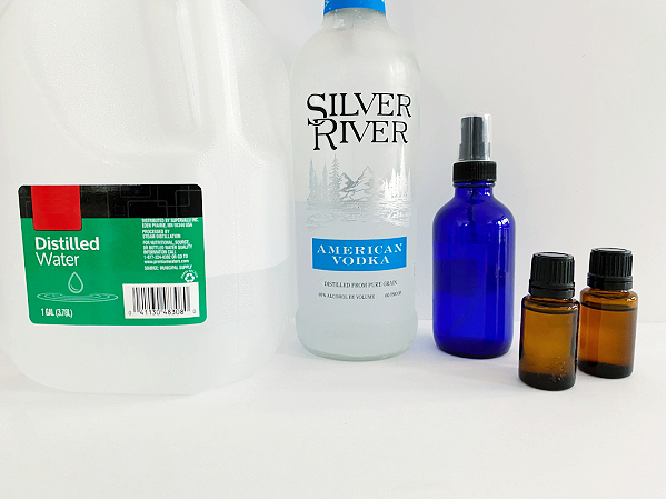 Ingredients and supplies needed to make an essential oil room spray: vodka, distilled water, and essential oil.