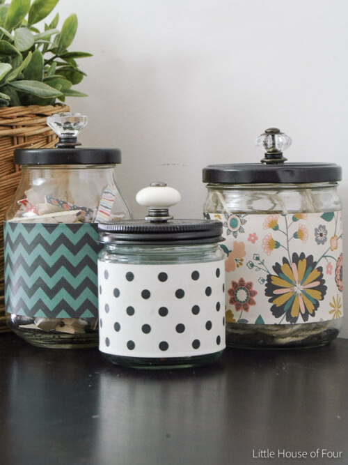 Small glass jars wrapped in scrapbook paper and topped with knobs to create cheap office organization