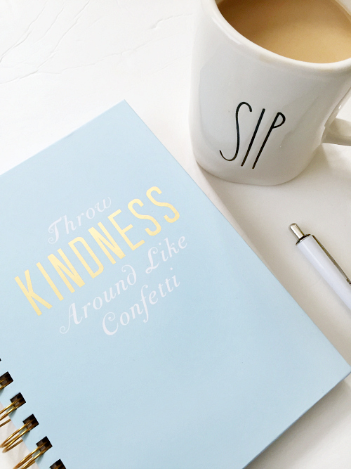 Notebook used for time management sitting by a cup of coffee