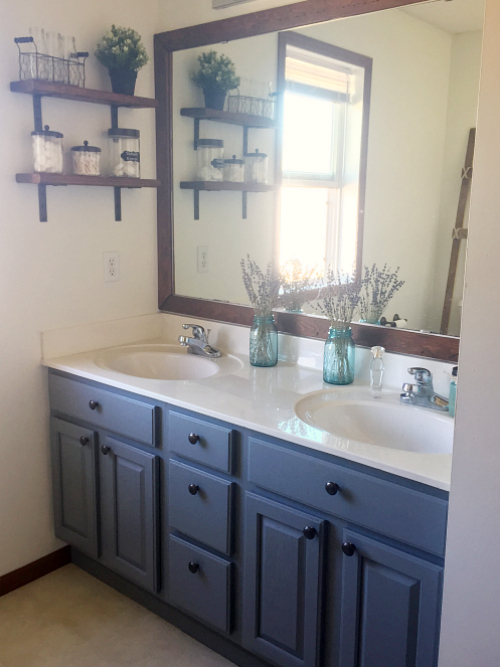 Farmhouse master bathroom updated for $100. Includes a blue/gray vanity, open shelving, and freshly painted walls.