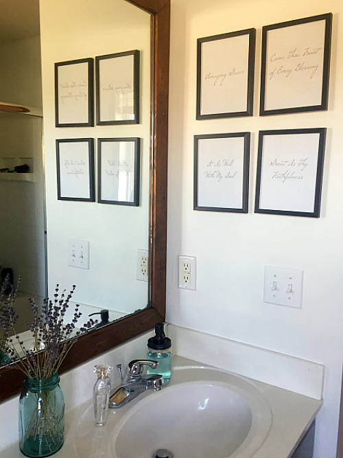 Gallery wall made with black framed hymn titles in farmhouse master bathroom