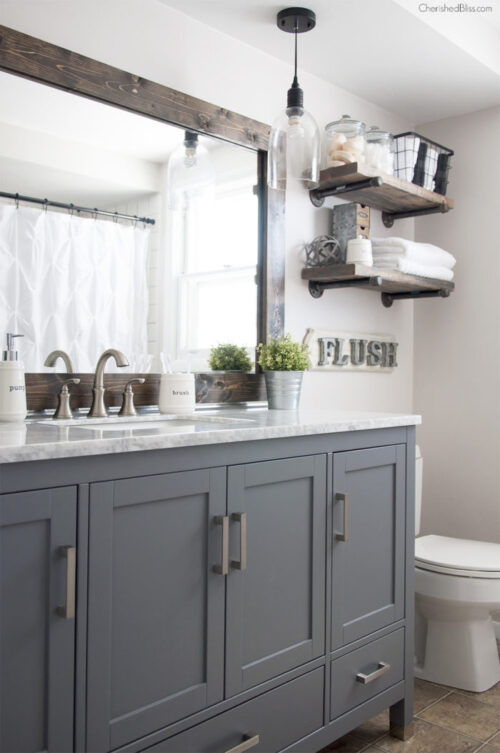 A framed mirror provides a farmhouse feel to the bathroom. Via Cherished Bliss.