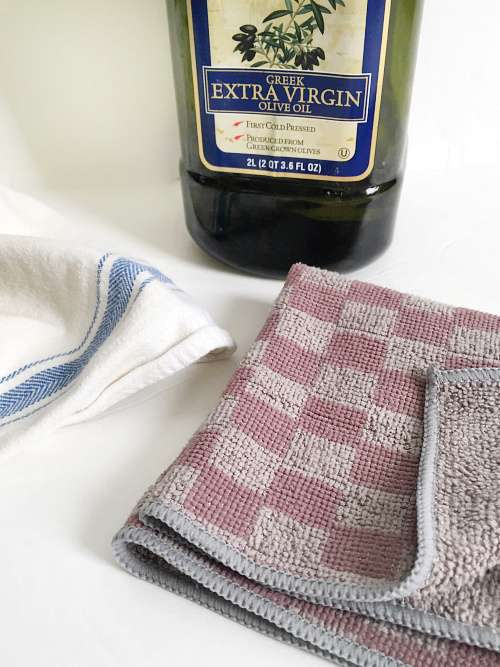 Items needed to clean stainless steel: microfiber cloth, dish towel, and olive oil