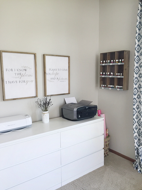 A view of the dresser area of this office makeover, which also displays a basket holding wrapping paper and a wall cubby housing essential oils