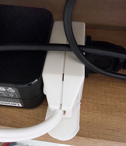 Extension cord adhered to the underside of a desk with a command strip. This hides the cords from being seen in the office