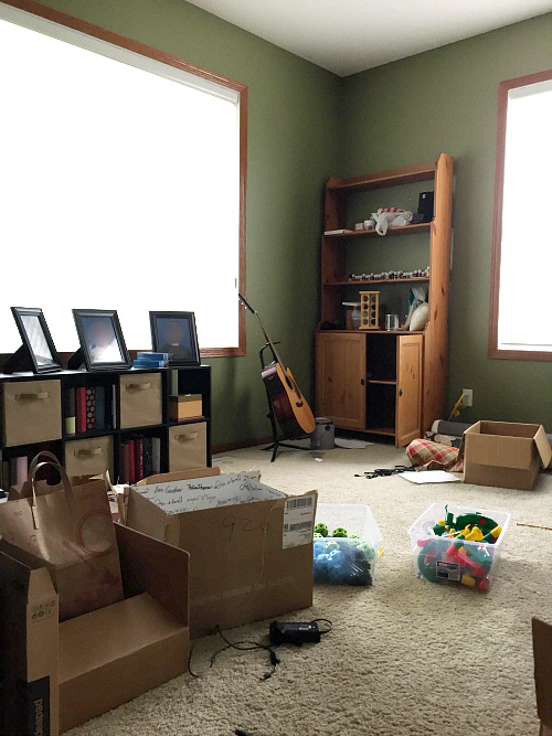 Office before makeover. Mismatched furniture, cardboard boxes everywhere, and green walls