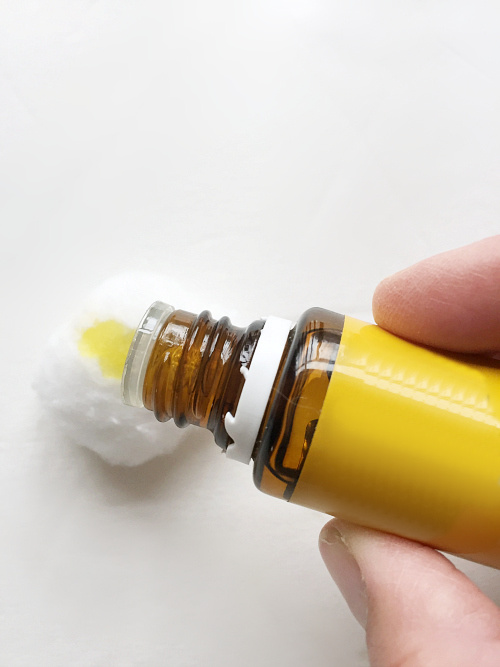 Adding lemon essential oil to a cotton ball