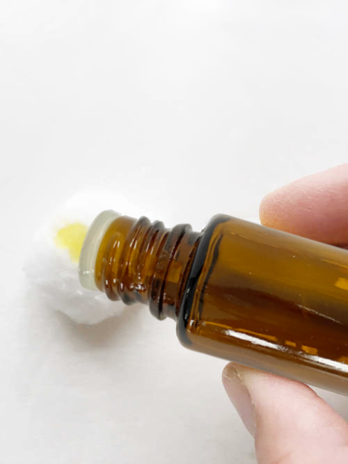 Applying lemon essential oil to a cotton ball.