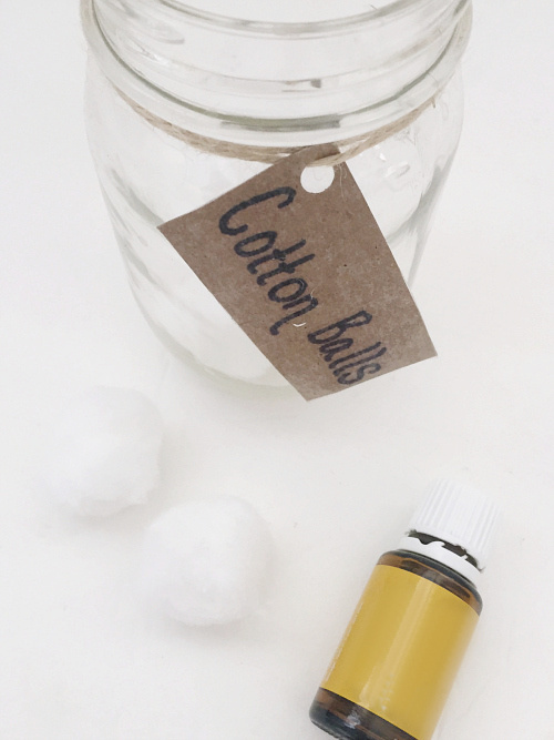 Bottle of lemon essential oil with a jar of cotton balls